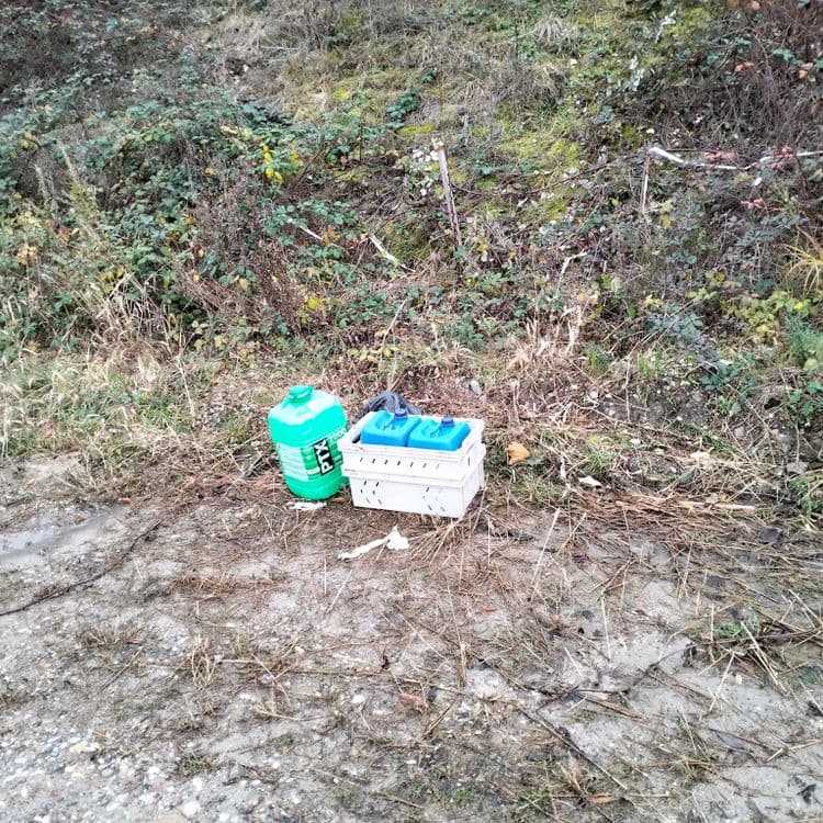 Plusieurs bidons vides abandonnés sur un terrain vague 