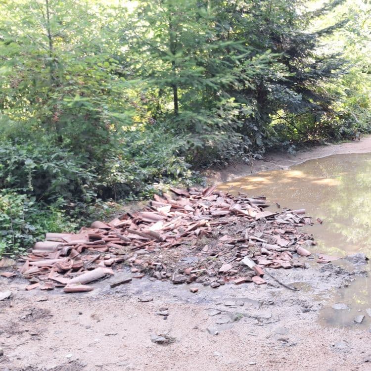 Sur la photo, on peut observer un dépôt sauvage constitué principalement de fragments de tuiles en terre cuite. La quantité de tuiles est importante, avec une estimation de plusieurs centaines de morceaux. Le poids total de ces tuiles est estimé entre 50 et 100 kilogrammes.