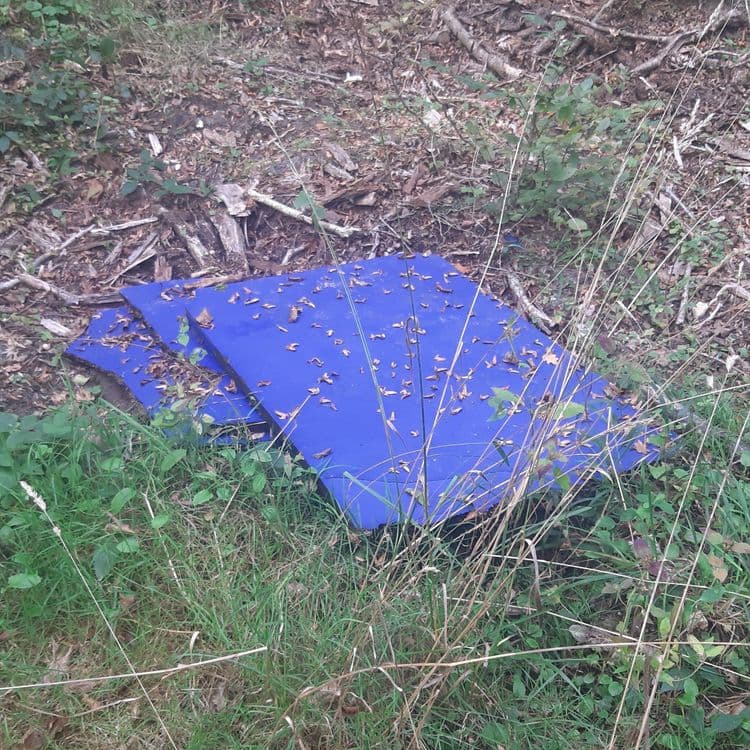 Voici l'analyse des déchets présents sur l'image :

On observe la présence de panneaux rigides en plastique bleu. On peut estimer la quantité à deux unités. Le poids total de ces panneaux est estimé à environ 5 kilogrammes.