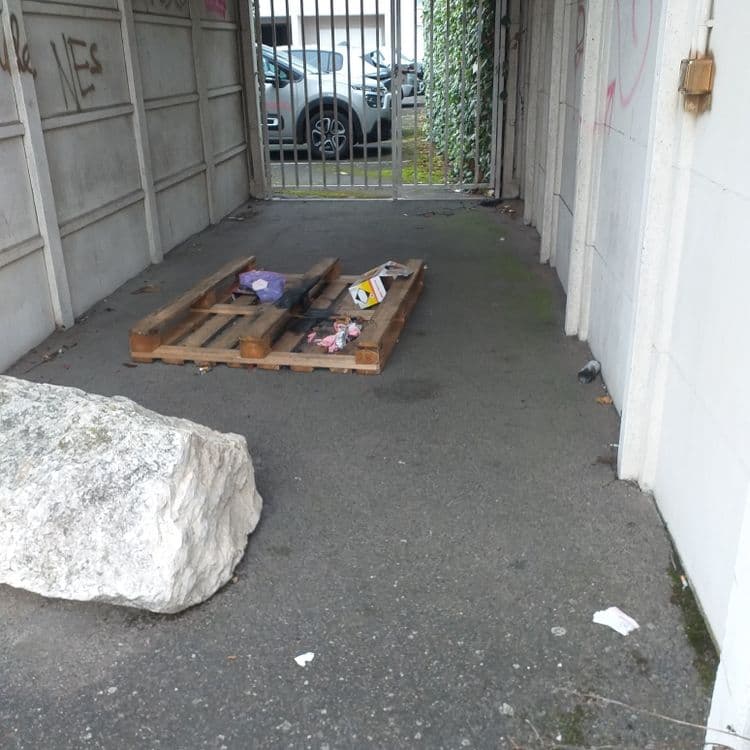 Dans toute l'allée, il y a de nombreux déchets qui jonchent le sol tel que mouchoirs, canettes en alu, plastiques, au bout de l'allée, un pneu avec une palette sous le petit abris avec nombreux cartons 