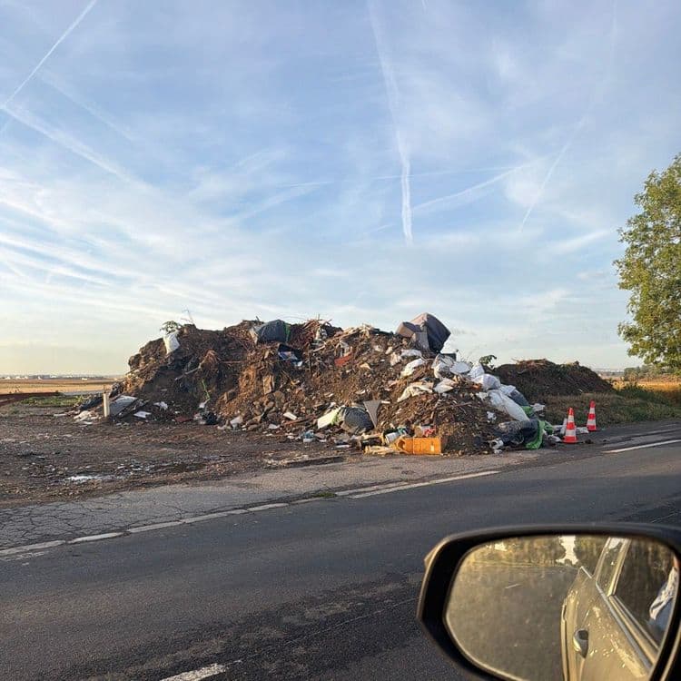 Voici un relevé des matériaux abandonnés sur le site :

*   **Terre et gravats :** Une masse importante constitue la base du dépôt. On estime la quantité à environ 15 à 20 mètres cubes, pour un poids total de 25 000 à 35 000 kilogrammes.
*   **Déchets verts :** Des branchages, des souches et des résidus végétaux sont mélangés à la terre et visibles en surface. La quantité est estimée à environ 3 à 5 mètres cubes, représentant un poids de 300 à 500 kilogrammes.
*   **Sacs de déchets mélangés :** De nombreux sacs poubelles, noirs et blancs, sont éparpillés sur le monticule. On dénombre une trentaine de sacs, de tailles variées, pour un poids total estimé entre 450 et 600 kilogrammes.
*   **Encombrants :** Un gros élément de mobilier, ressemblant à un matelas ou un canapé, est visible, ainsi que d'autres pièces de bois et de plastique de grande taille. La quantité est d'environ 3 à 5 pièces majeures, avec un poids total de 150 à 250 kilogrammes.
*   **Plastiques divers :** Des seaux, des bidons, des fragments de bâches et d'autres emballages plastiques sont présents. On estime une dizaine de pièces distinctes, pour un poids d'environ 50 à 80 kilogrammes.
*   **Métaux :** Quelques morceaux de ferraille et de profilés métalliques sont identifiables. La quantité est de quelques éléments, avec un poids estimé entre 50 et 100 kilogrammes.
*   **Cartons :** Des emballages en carton, dont une caisse orange bien visible, sont dispersés. On compte quelques unités, pour un poids d'environ 10 à 20 kilogrammes.