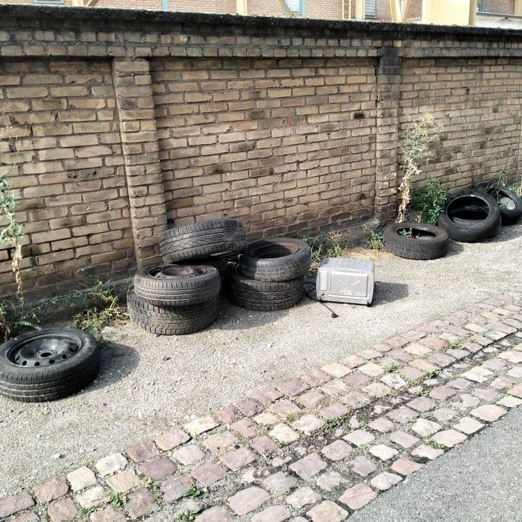 Pneus usagés et un mini four abandonnés au bord de la route en zone industrielle 