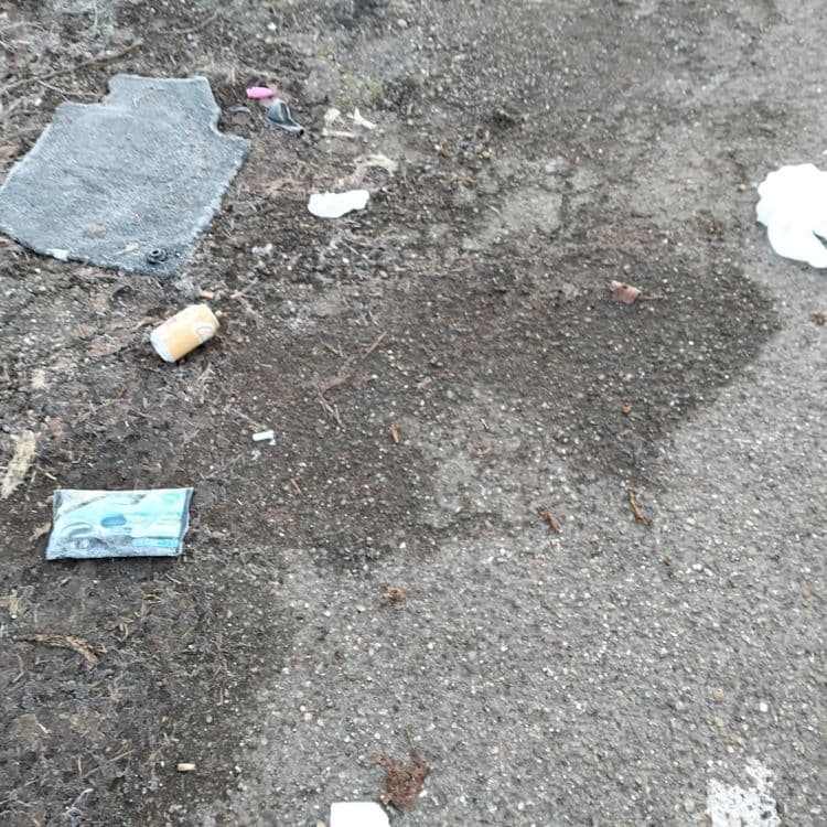 Déchets divers abandonnés sur une route d'accès à un terrain privé 