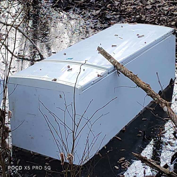 Je constate de gros frigo avec congélateur intégré, un pare-choc de voiture, des bidons de contenant, un chauffage à fioul, et divers déchets dans une retenue d'eau au bord de l'Oise en arrière du chemin.