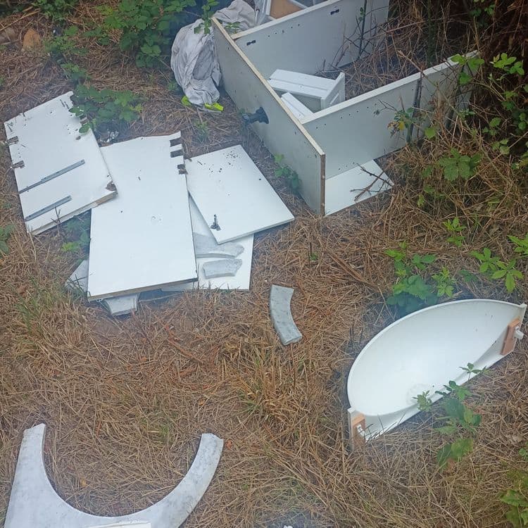 Meubles de salle de bain jeté au sol et divers déchets.