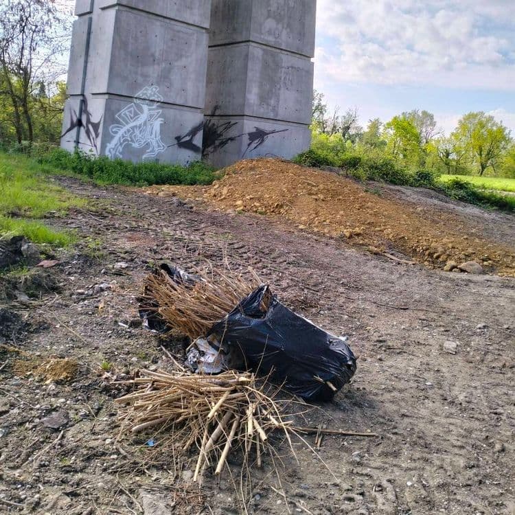Sacs poubelles abandonnés sur un chemin passant sous un pont 