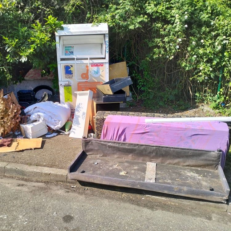 Pneus usagés, frigo, mobilier, déchets divers à côté de containers à vêtements.