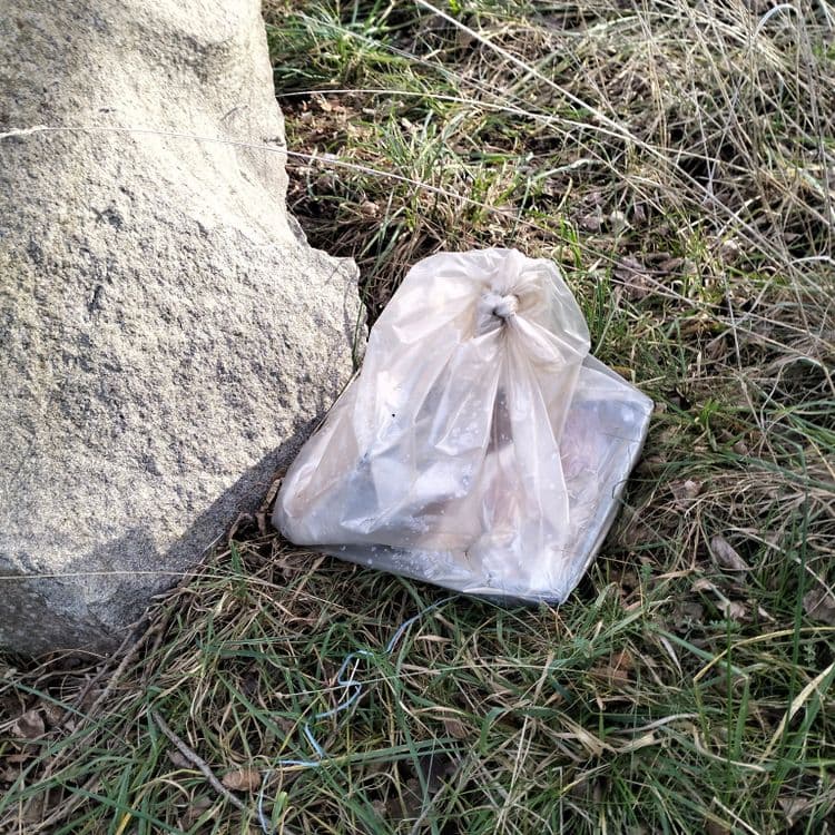 Un sac poubelle abandonné au bord de la route en zone industrielle 