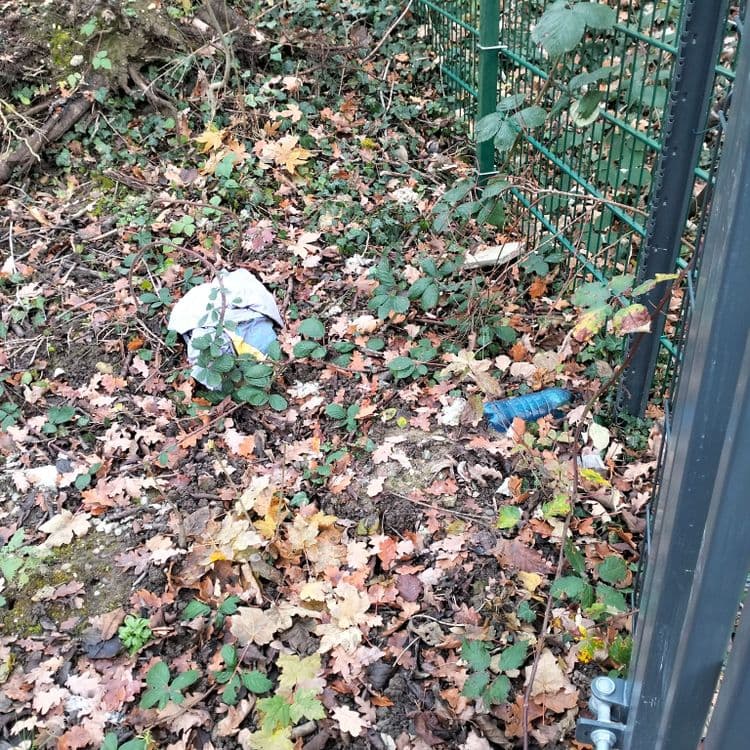 Déchets divers sur un parking et en bas de talus ferroviaire, en zone artisanale 