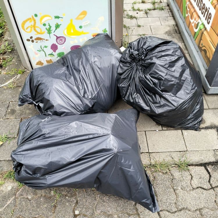 Sacs poubelles abandonnés à côté de containers à verre et bio déchets 