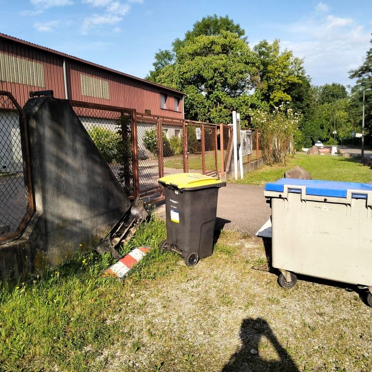 Pare choc et pièce plastique à côté de poubelles 