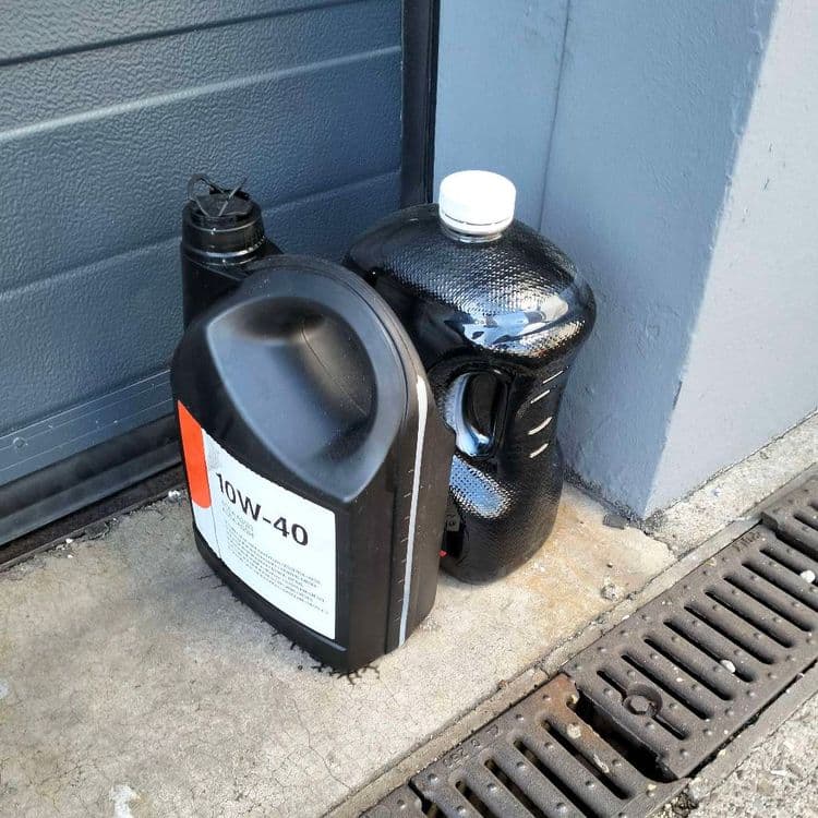 Deux bidons d'huile usagée abandonnés devant les portes d'un garage Norauto 