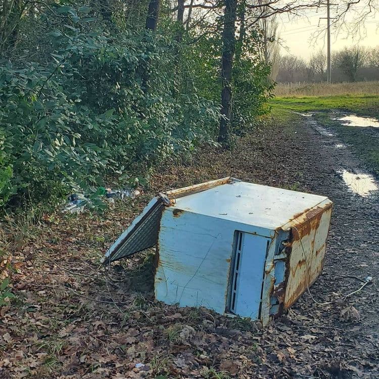 Voici une analyse des déchets présents sur l'image :

*   **Gros électroménager** : Un réfrigérateur ou congélateur abandonné est visible. Son poids estimé est d'environ 50 kg à 80 kg. Il s'agit d'une seule unité.

*   **Déchets ménagers divers** : Une quantité non négligeable de déchets ménagers épars est présente, comprenant des bouteilles en plastique, des canettes en aluminium et divers emballages. Le poids total estimé de ces déchets est d'environ 5 kg à 10 kg. On peut estimer une dizaine de bouteilles et canettes, ainsi qu'un volume équivalent d'emballages divers.