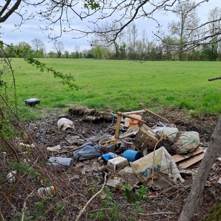 Déchets divers au pied de la haie dans un champ et au bord d'un chemin de randonnée 