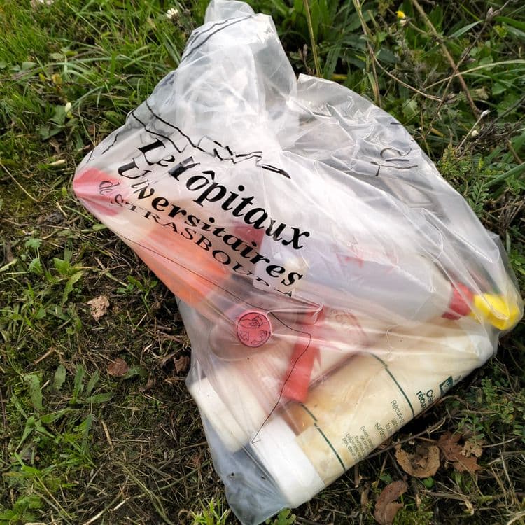 Sac poubelle au bord de la route avec différents produits liquides à l'intérieur 