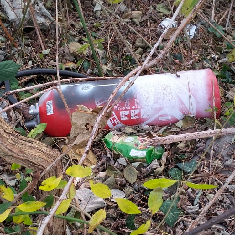 Pièces détachées pour automobile, pneu usagé, restes mobilier, déchets divers sur un terrain vague à proximité de constructions neuves 