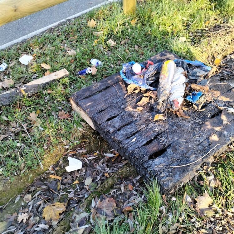 Palette et déchets divers brûlés au bord d'une piste cyclable 