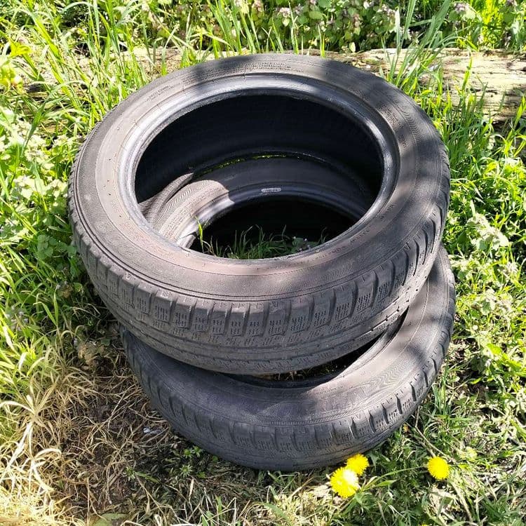 Pneus usagés abandonnés au bord d'une route en zone industrielle 