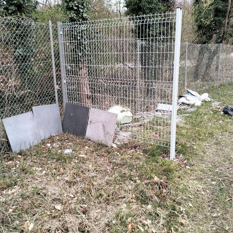 Restes de carrelage et déchets divers abandonnés sur un chemin en lisière de forêt 