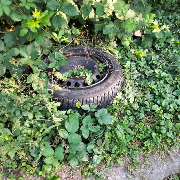 Pneu usagé et déchets divers abandonnés sur un parking public 