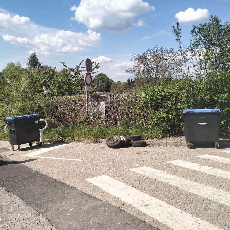 5 roues complètes abandonnées dans la rue à côté de containers à déchets 