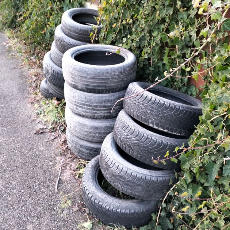 Stock de pneus usagés abandonnés sur le trottoir 