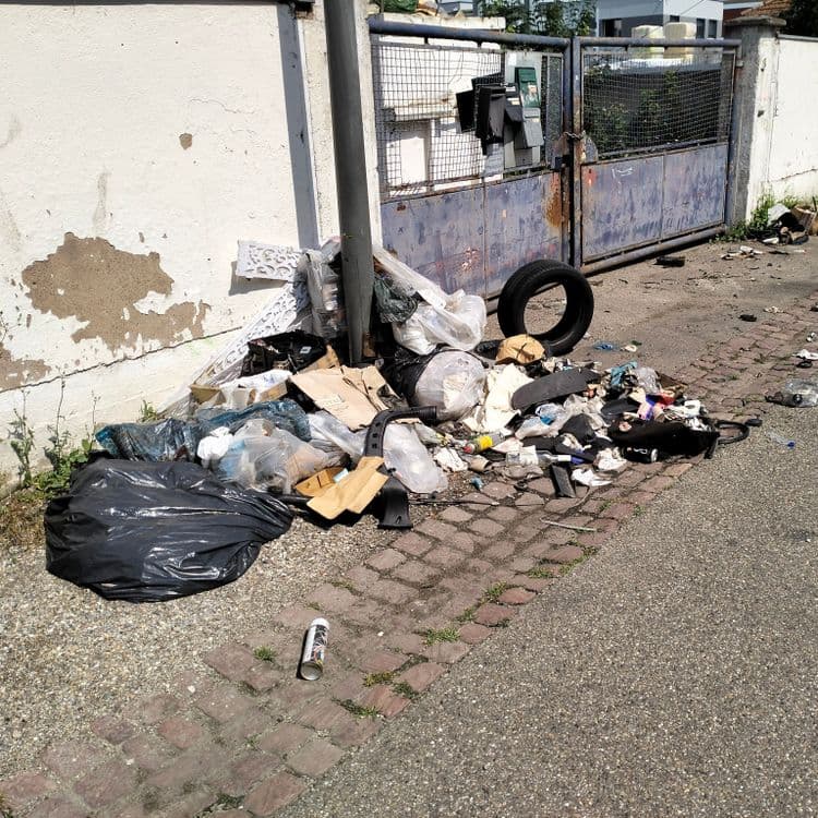 Pneus usagés et déchets divers devant un bâtiment en cours de démolition 