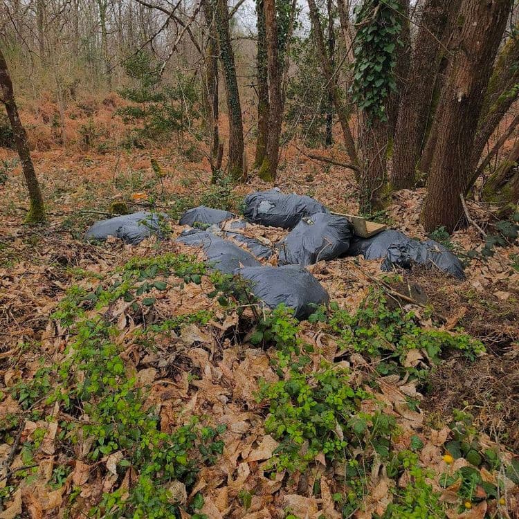 Nombreux sacs poubelles a l'angle de la clôture en barbelés.