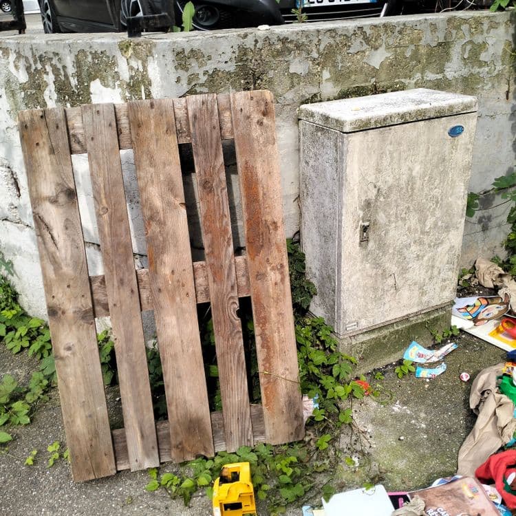 Palette, jouets, déchets divers sur le trottoir 