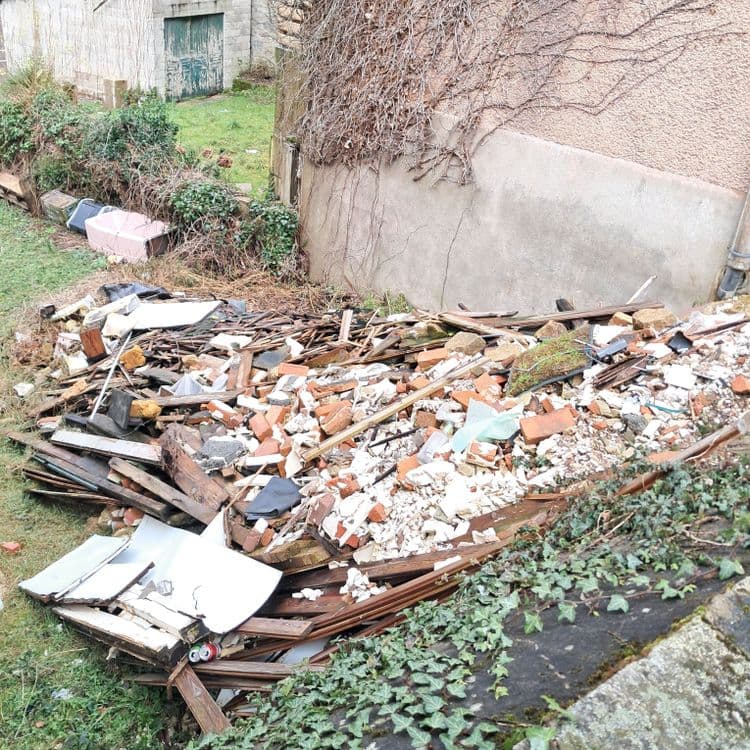 Voici les déchets visibles sur la photo :

* Bois : poutres, planches, débris de bois.
* Briques : nombreuses briques cassées et entières.
* Béton : morceaux de béton et de mortier.
* Débris divers :  morceaux de plaques (plastique?), métaux, et autres débris de construction.
* Une baignoire.

Il semble que les déchets proviennent de la démolition ou de la rénovation d’un bâtiment.

