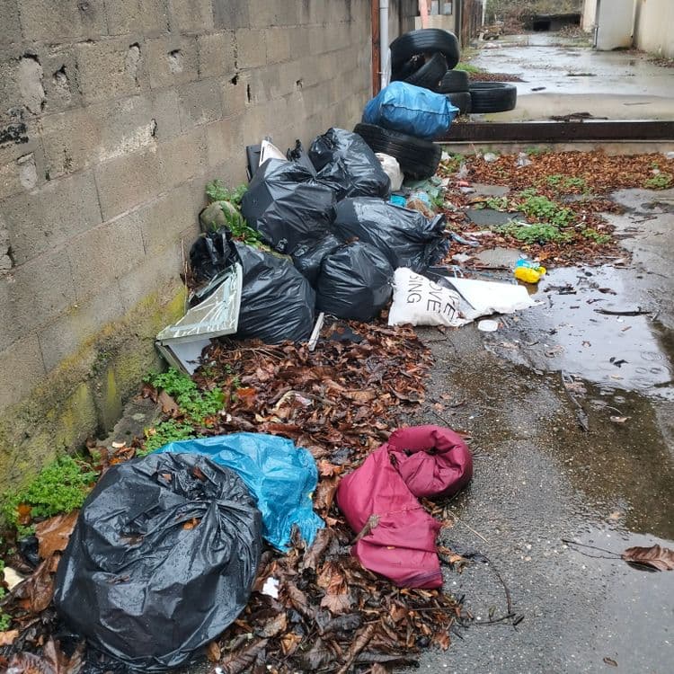 Pneus usagés et pièces automobiles et déchets divers abandonnés aux abords d'un entrepôt désaffecté 