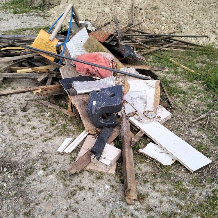 Bois et déchets divers abandonnés sur un chemin au milieu des champs 