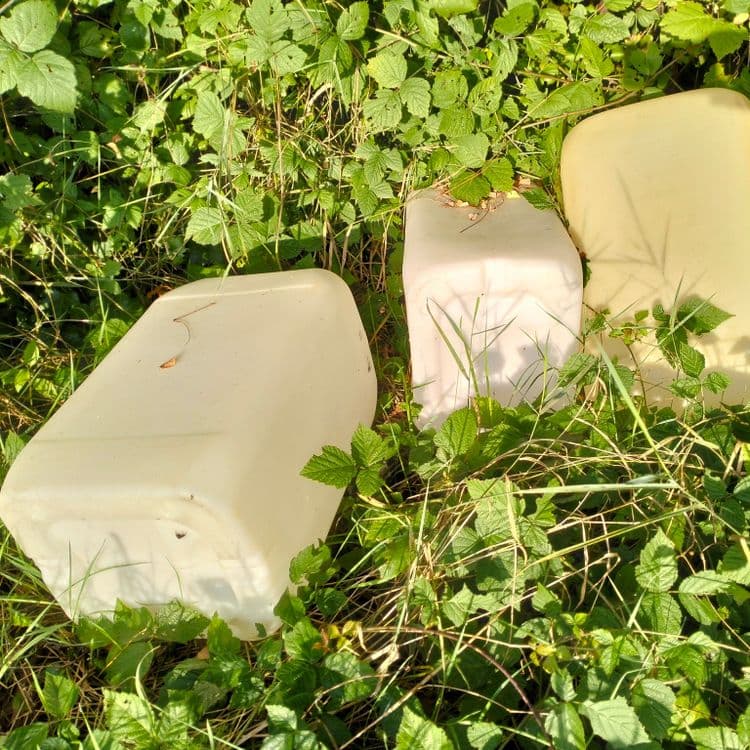 3 bidons plastique vides au bord de la route dans les fourrés 