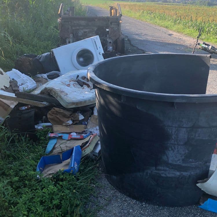 Une carcasse de voiture calcinée, des encombrants, une machine à laver, 
du plastique  