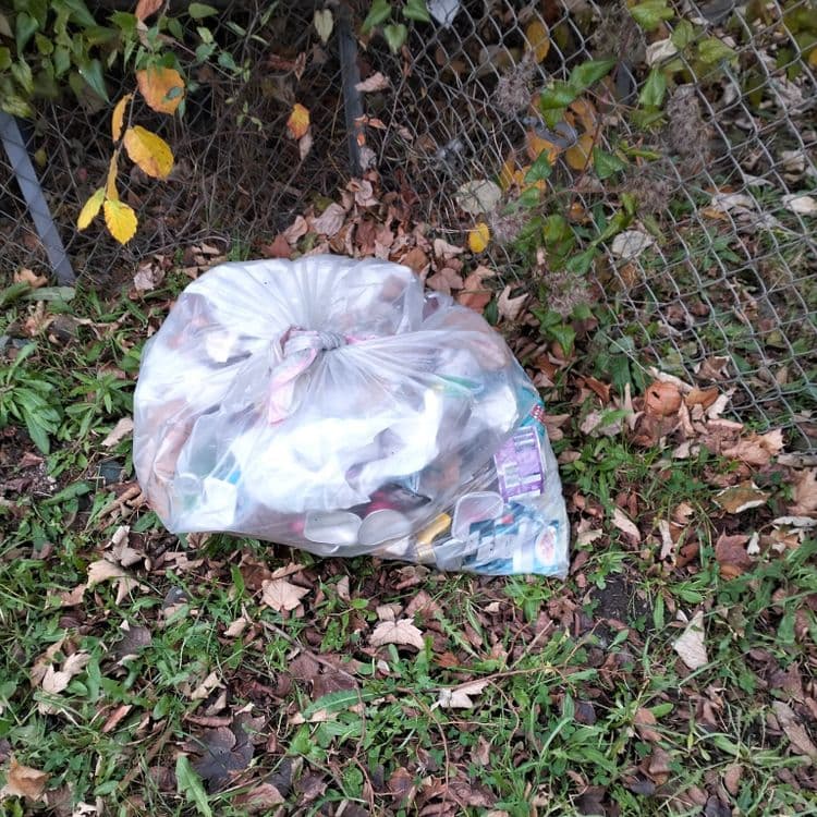 Sac poubelle placé devant le portail de jardins ouvriers 
