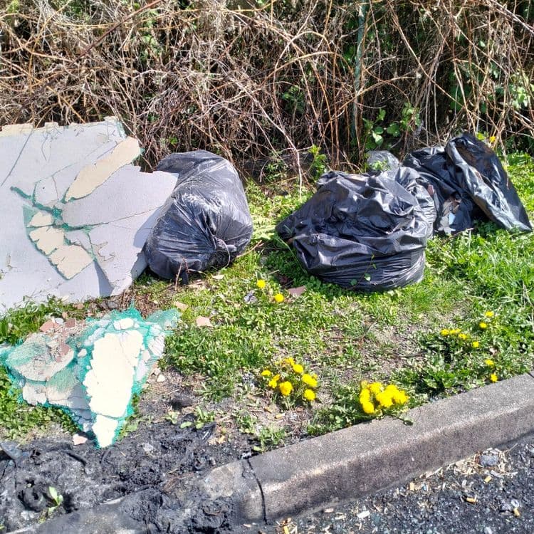 Sacs poubelles et déchets divers abandonnés sur un parking de supermarché 