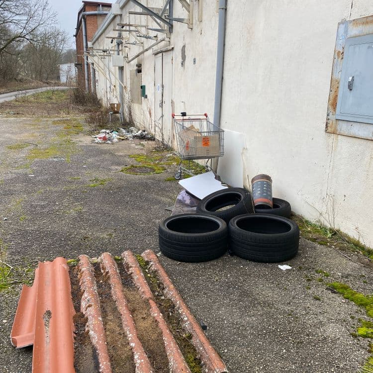 Je contacte 8 pneus des sacs poubelles et de nombreux déchets à proximité tels que tablette salon jardin papier plastique une clôture de chantier 