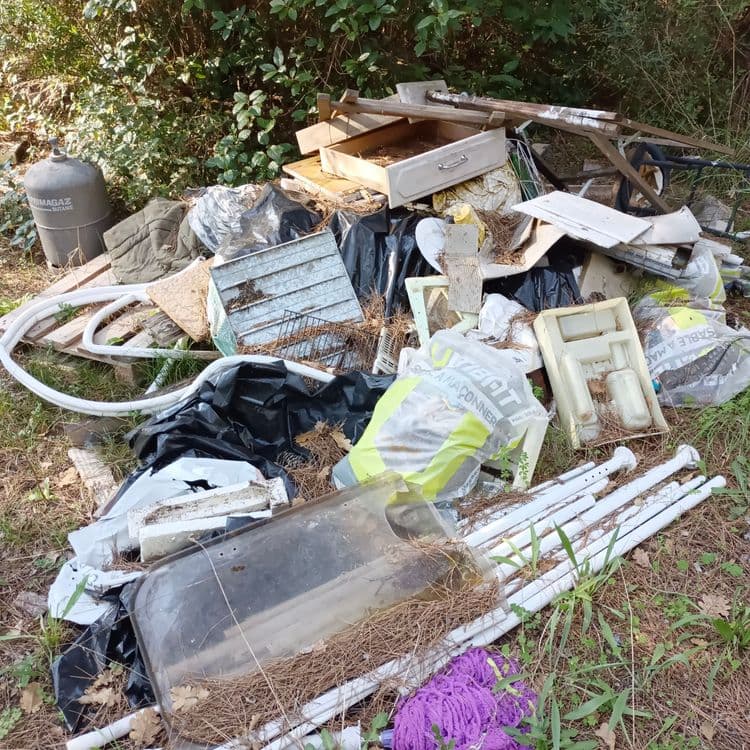 Voici une estimation des déchets présents sur l'image, incluant le type, la quantité et une estimation du poids :

*   **Déchets encombrants divers** : Une quantité importante de déchets hétéroclites, incluant des morceaux de meubles (tiroirs, portes), des éléments de literie, des plastiques divers, du bois et des matériaux d'isolation. Le poids total de cet ensemble est estimé à environ 50 kg.
*   **Sacs poubelles** : Plusieurs sacs poubelles noirs de taille moyenne sont visibles. Le contenu est inconnu, mais on peut estimer un poids moyen de 5 kg par sac, soit environ 15 kg au total.
*   **Tuyaux PVC** : Un ensemble de tuyaux en PVC blanc est présent. La quantité est d'environ 6 tuyaux, pour un poids total d'environ 5 kg.
*   **Bouteille de gaz** : Une bouteille de gaz PRIMAGAZ est visible. En fonction du modèle, le poids peut varier entre 10 et 15 kg. Estimons un poids de 12 kg.
*   **Déchets textiles** : Un amas de textile violet, probablement un vieux vêtement ou un chiffon est visible. On peut estimer son poids à 1 kg.
*   **Matériaux de construction/rénovation** : Divers éléments semblent provenir de travaux de construction ou de rénovation (grillage). On peut estimer le poids total de ces déchets à 10 kg.

En résumé, le poids total des déchets présents sur l'image est estimé à environ 98 kg.