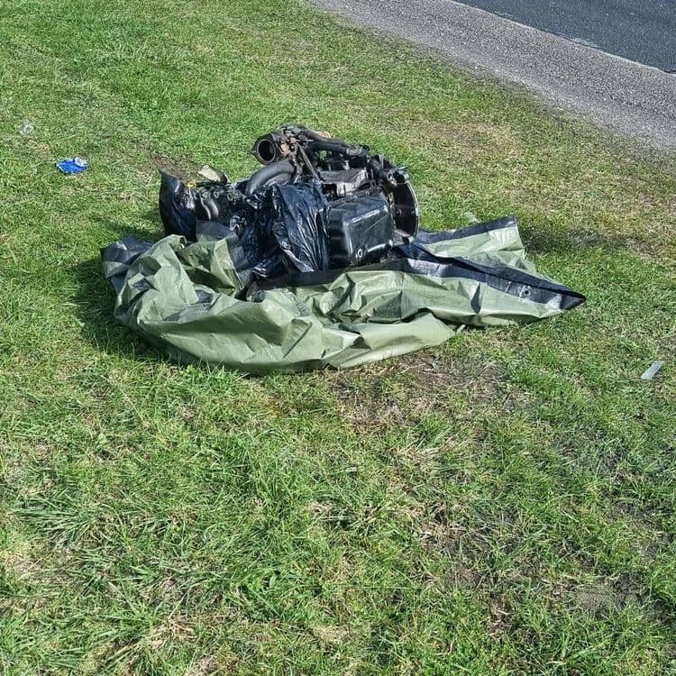 Voici l'analyse des déchets présents sur l'image :

Un moteur de véhicule, estimé à environ 150 kg, est visible. L'ensemble repose sur une bâche verte, d'un poids estimé à 2 kg. Un petit déchet bleu, probablement un morceau de plastique ou de tissu, est également visible, son poids est négligeable.
