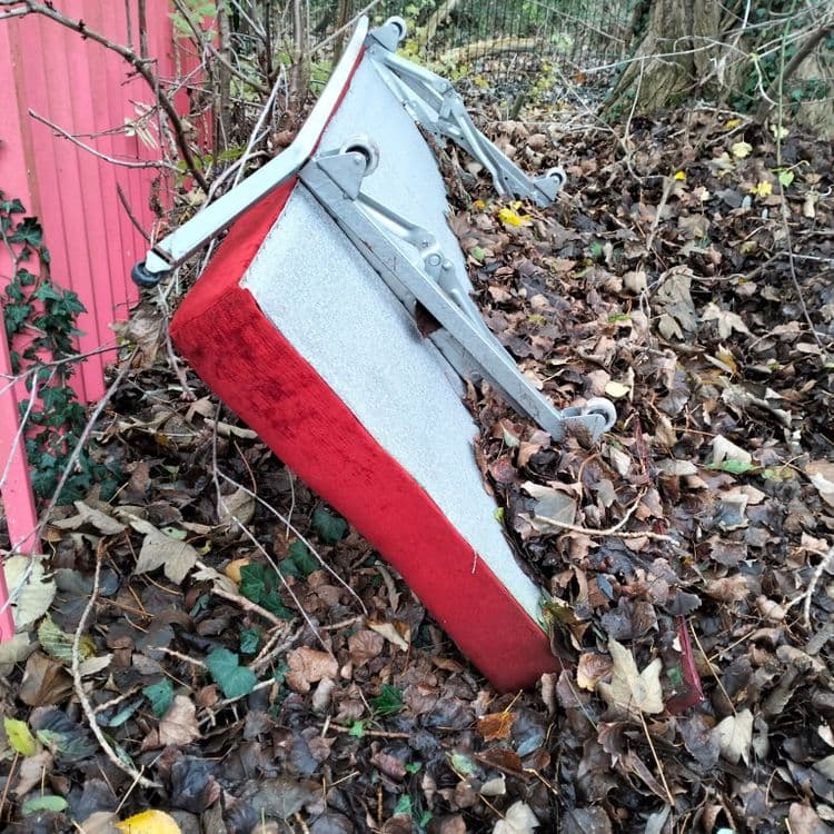 Un couffin et une banquette abandonnés à proximité d'un portail d'entreprise 