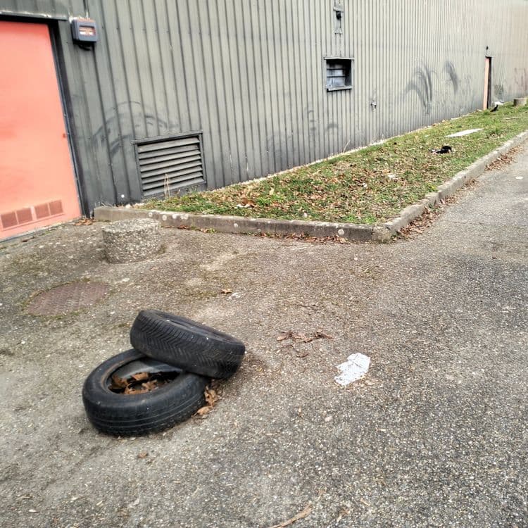 Pneus usagés et déchets divers aux quatre coins d'un parking d'un ancien garage Norauto ayant fermé ses portes 