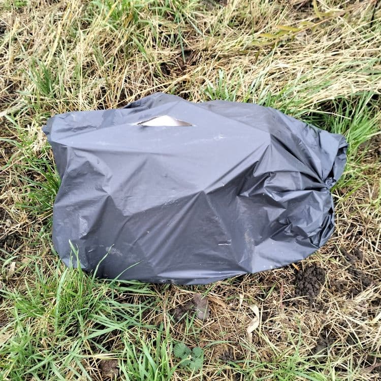 Sac poubelle abandonné dans un champ 