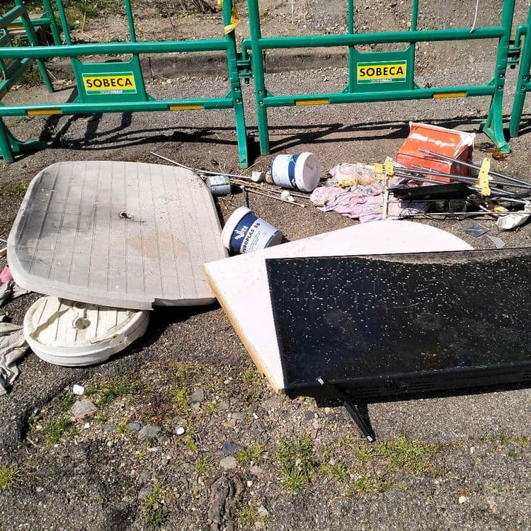 Déchets divers abandonnés sur un parking public à l'arrière d'un lycée 