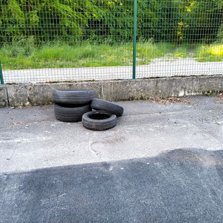 Pneus usagés abandonnés sur un parking public 