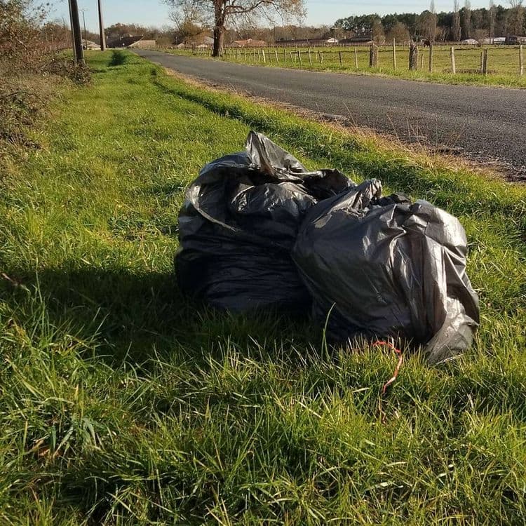 Deux sacs poubelles non éventré placés sur le côté de la route. Facile a ramasser et transporter.