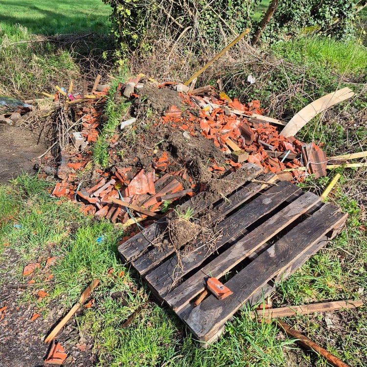 Voici une estimation des déchets présents sur l'image :

*   **Débris de tuiles en terre cuite :** Environ 50 kg. On observe une quantité importante de fragments de tuiles, suggérant peut-être une toiture endommagée ou des restes de travaux.

*   **Bois divers (planches, tasseaux, etc.) :** Environ 10 kg. Il semble y avoir des chutes de bois, potentiellement issues de travaux de construction ou de démolition.

*   **Terre et végétaux (racines, herbe arrachée) :** Environ 15 kg. La présence de terre et de végétaux indique probablement un nettoyage de jardin ou un terrassement sommaire.

*   **Palette en bois :** Environ 20 kg. Une palette entière est présente.

*   **Divers (petits débris non identifiables) :** Environ 5 kg. Une estimation pour les petits éléments non identifiés.

*   **Marteau :** Environ 1 kg. Un marteau est visible.

