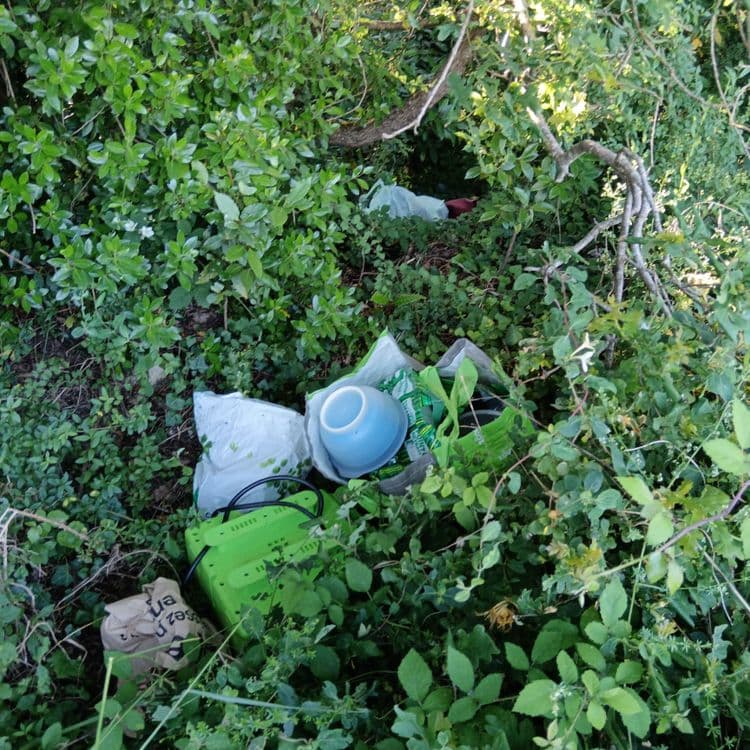 Des déchets sur le sol, des casseroles, un chargeur de batterie et des poches de nourriture ainsi que des canettes de bière.