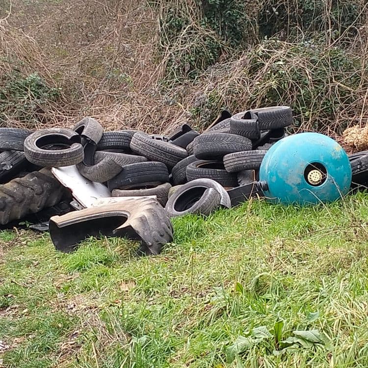 Pneus usagés abandonnés au bord d'une impasse et d'habitations précaires 