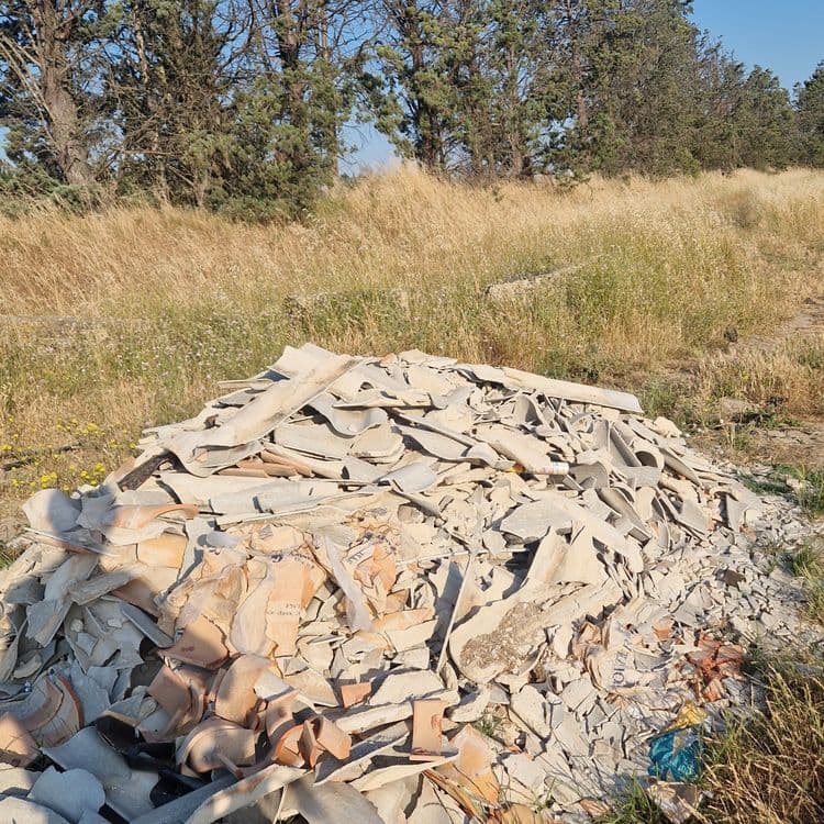 Voici une estimation des déchets présents sur la photo :

*   **Tuiles cassées (terre cuite et béton)** : Environ 150 kg, représentant un volume important de fragments de tuiles diverses.

*   **Sacs en plastique et déchets d'emballage** : Environ 2 kg, correspondant à quelques sacs et résidus d'emballages divers.
