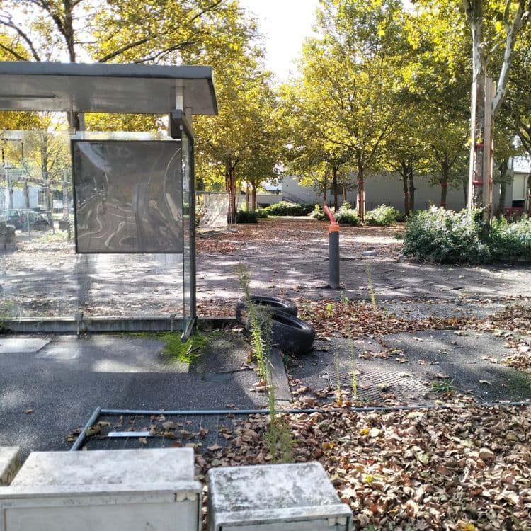 Deux pneus usagés sur un parking public, à côté d'un abri 